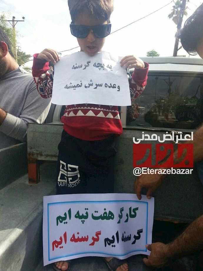 A child of a Haft Tappeh employee holds a sign reading: “A hungry child could care less about a promise”