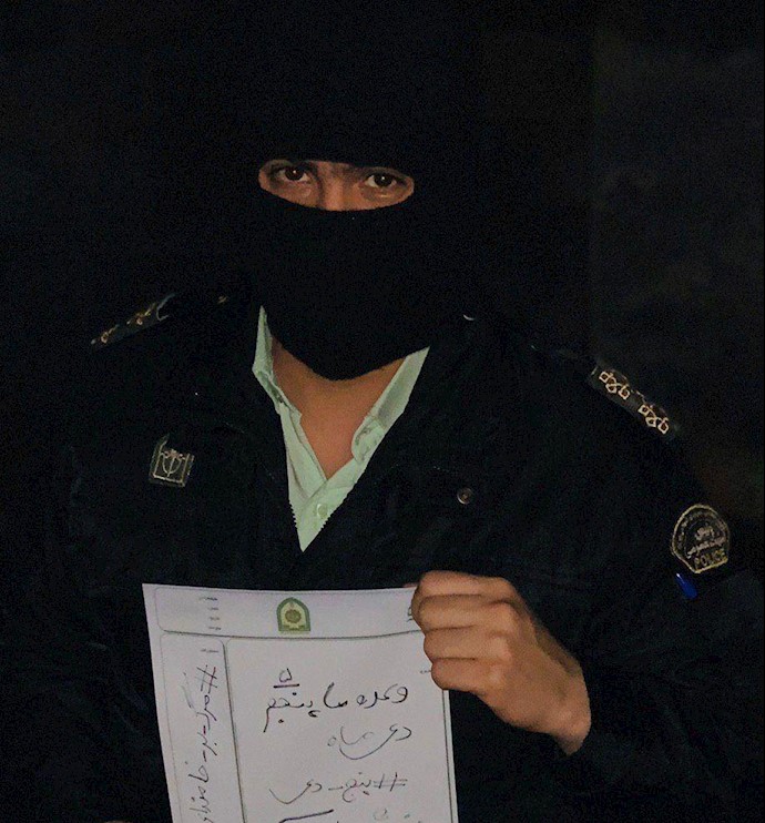 An Iranian regime security forces hold a paper reading Down with Khamenei