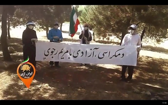 A group of MEK supporters holding a banner reading, “Democracy and freedom with Maryam Rajavi”